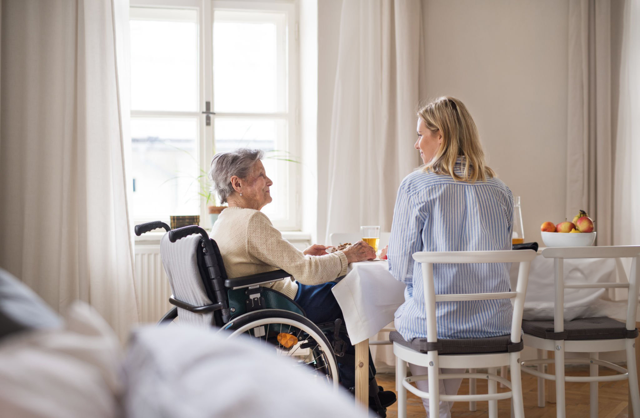 Older adult and caregiver sharing a meal; shared stock placeholder